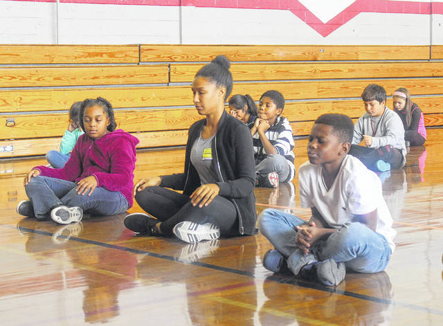 Nicole meditating with students at a school